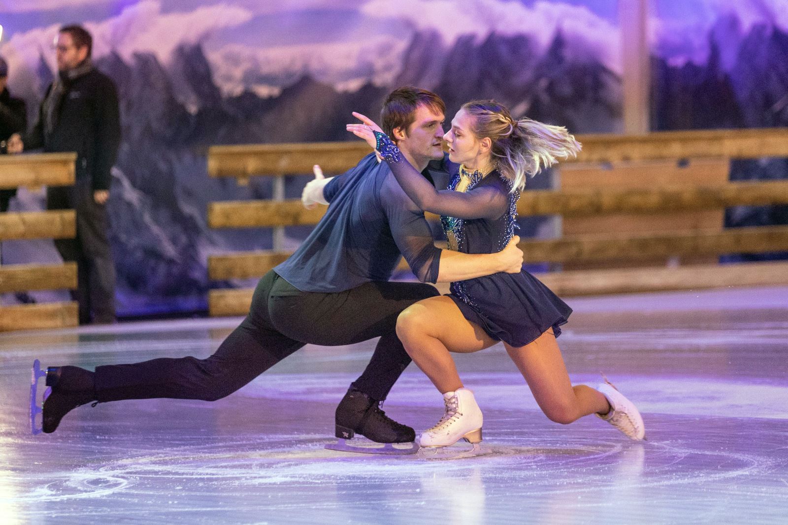 A man and a woman in ice dance costumes performing an ice dance routine